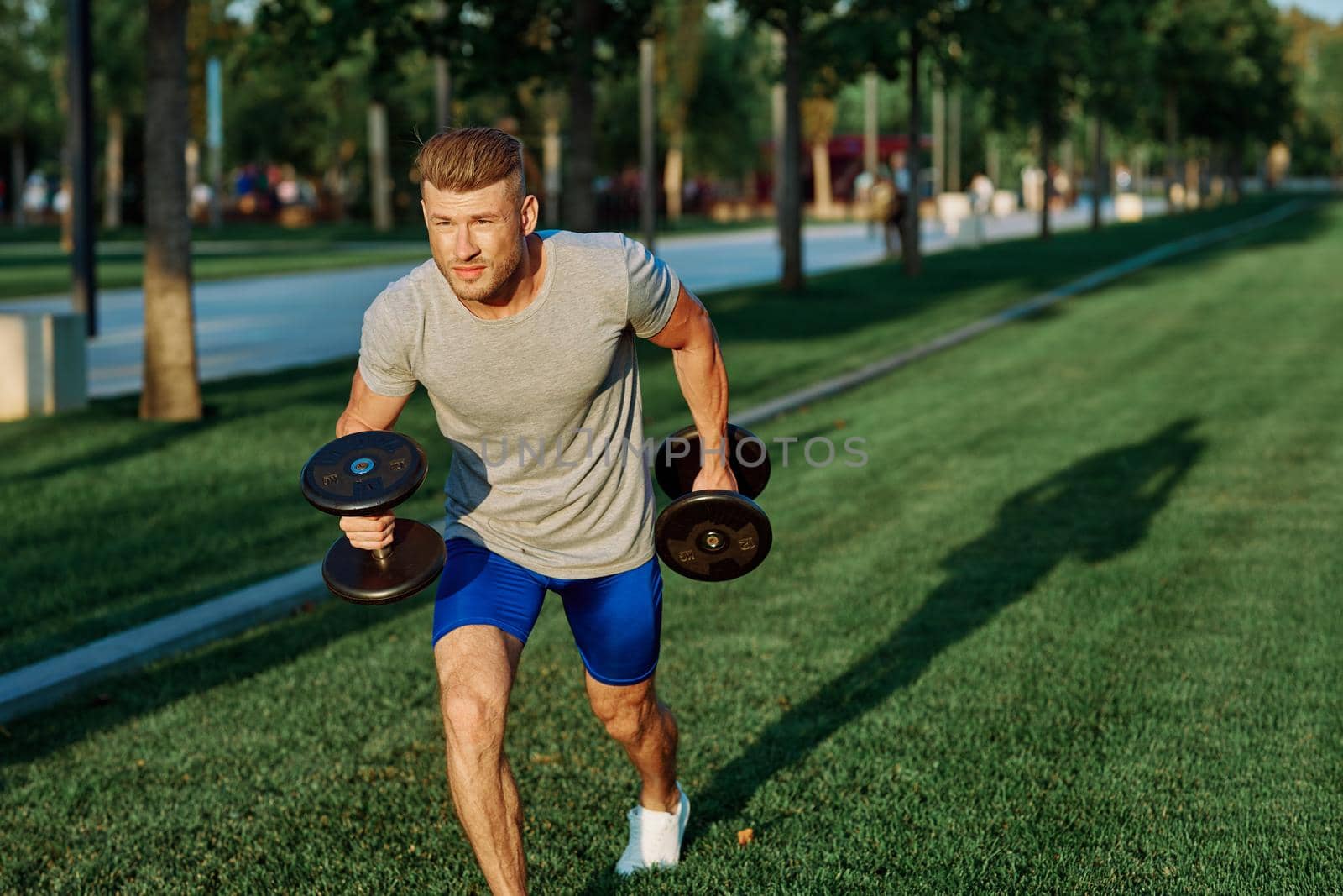 male athlete park with dumbbells doing CrossFit exercise by Vichizh