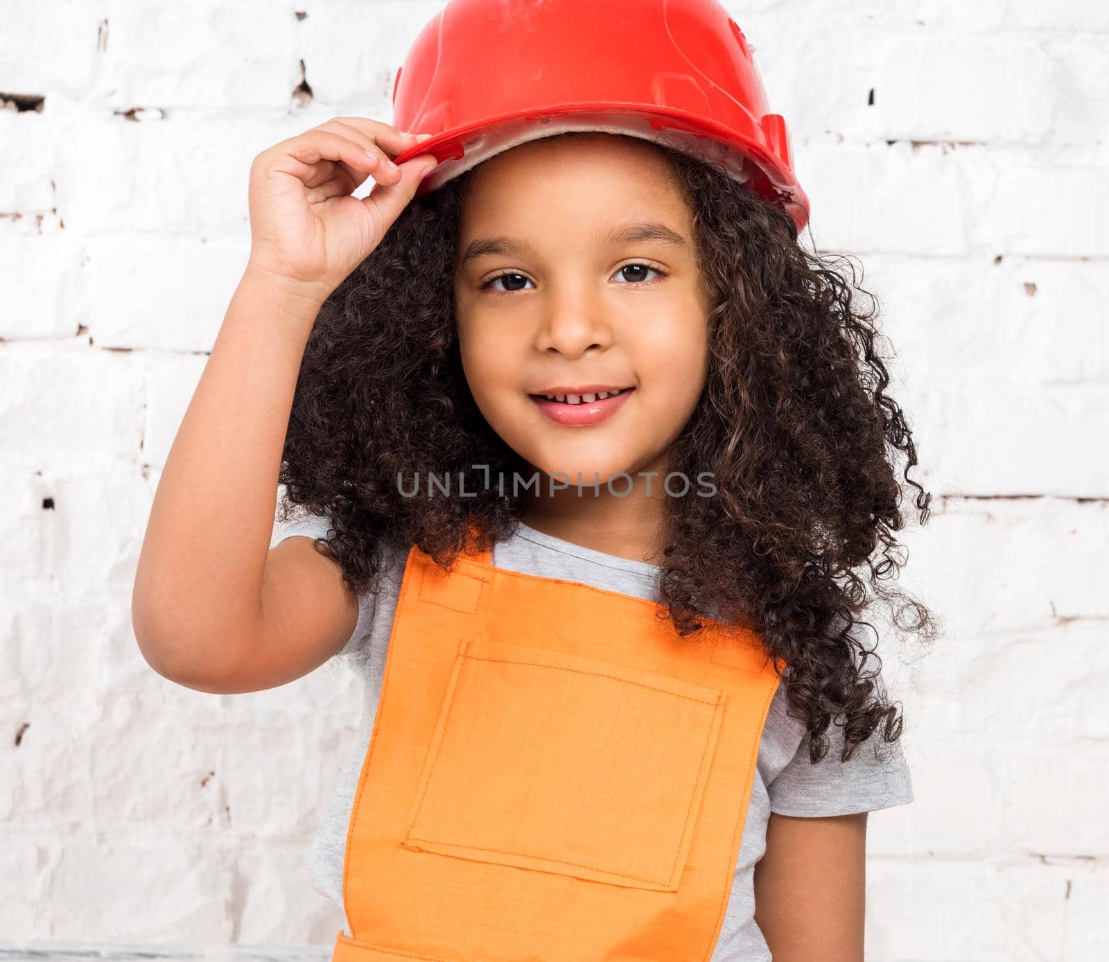 cute little girl in orange repairmen uniform and helmet