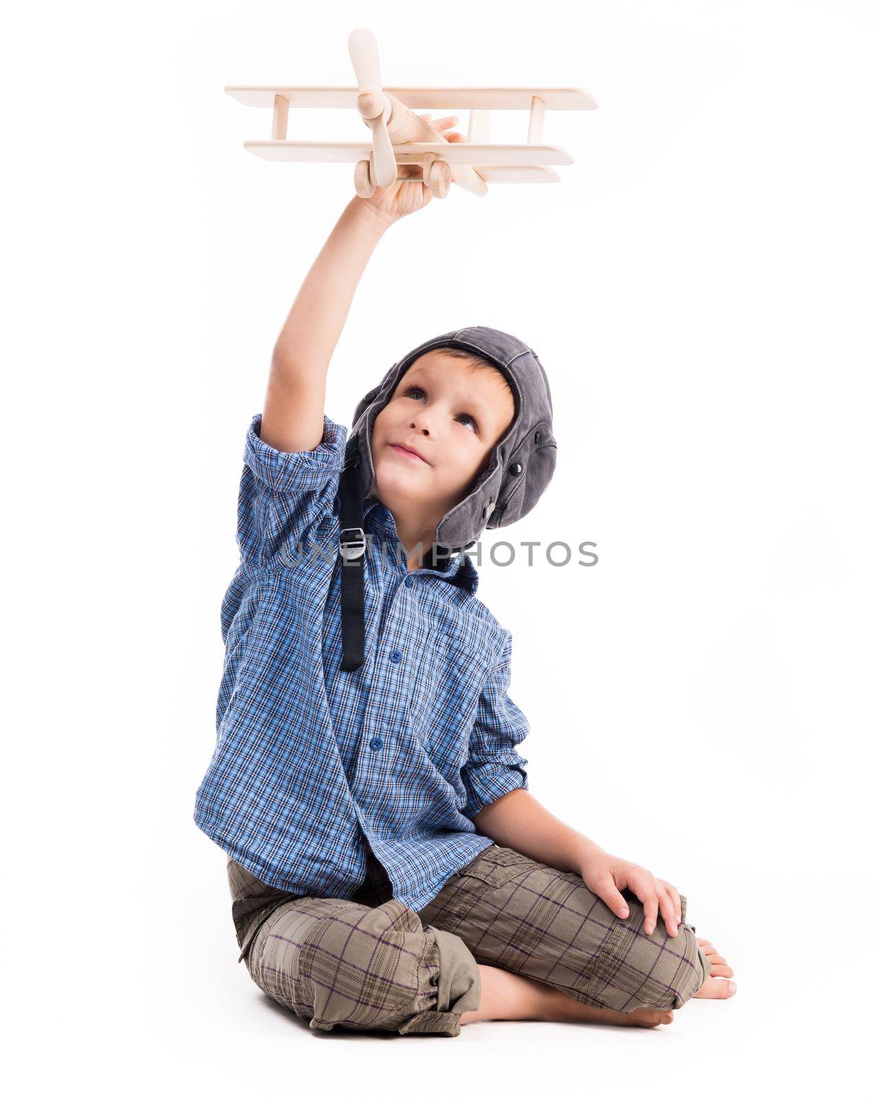 little boy with pilot hat and toy airplane sitting isolated on white background