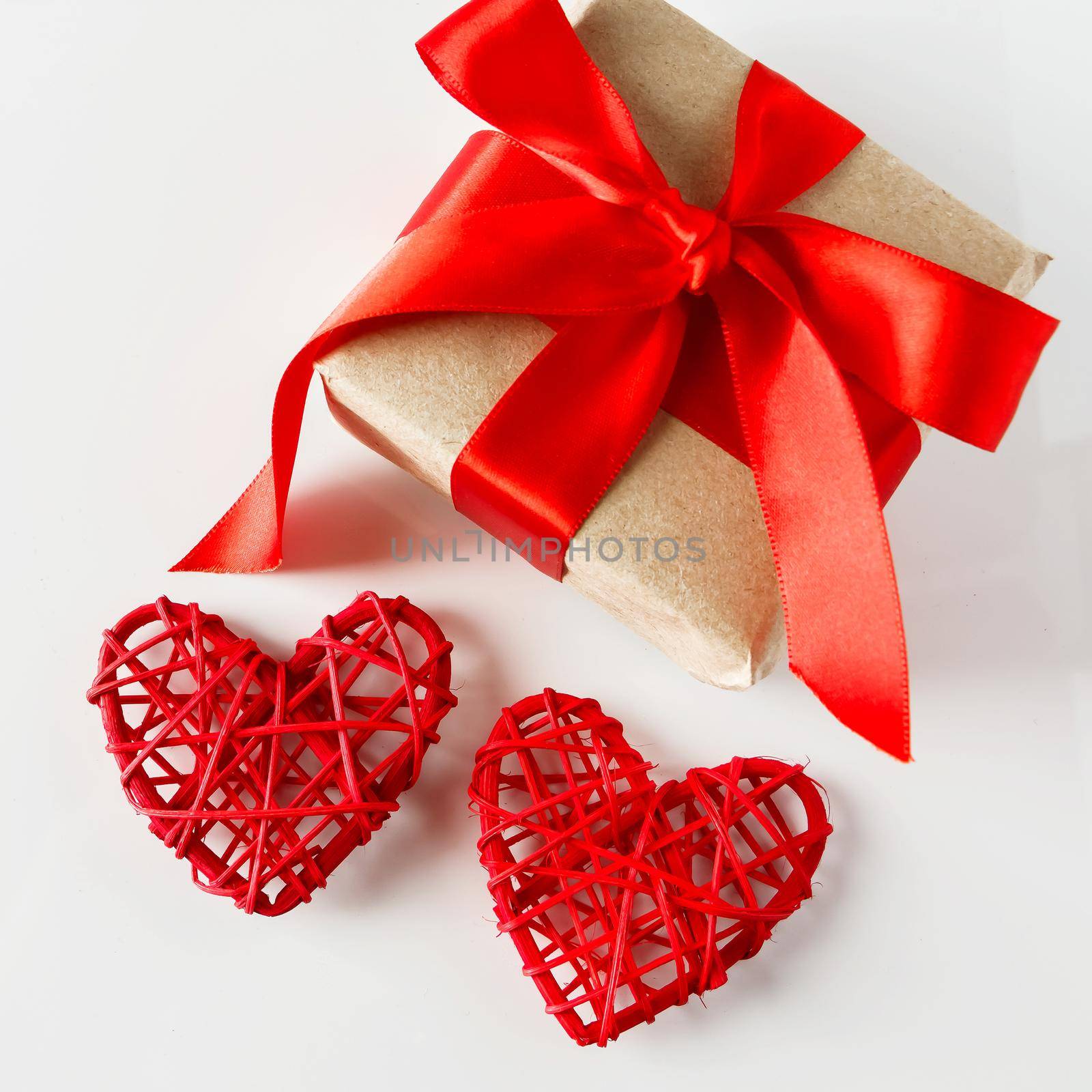 Valentine's day gift and red hearts on a white background. Valentine's day surprise with red ribbon and 2 hearts close-up on a white background