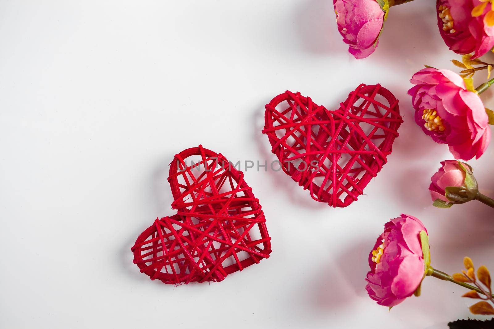 Flowers and red hearts on a white background for Valentine's Day. Two red hearts and delicate pink flowers on a white background
