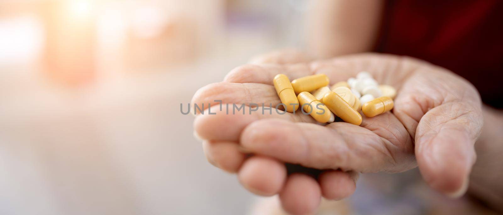 Senior woman hands filled with pills closeup. Elderly female person with drugs at home