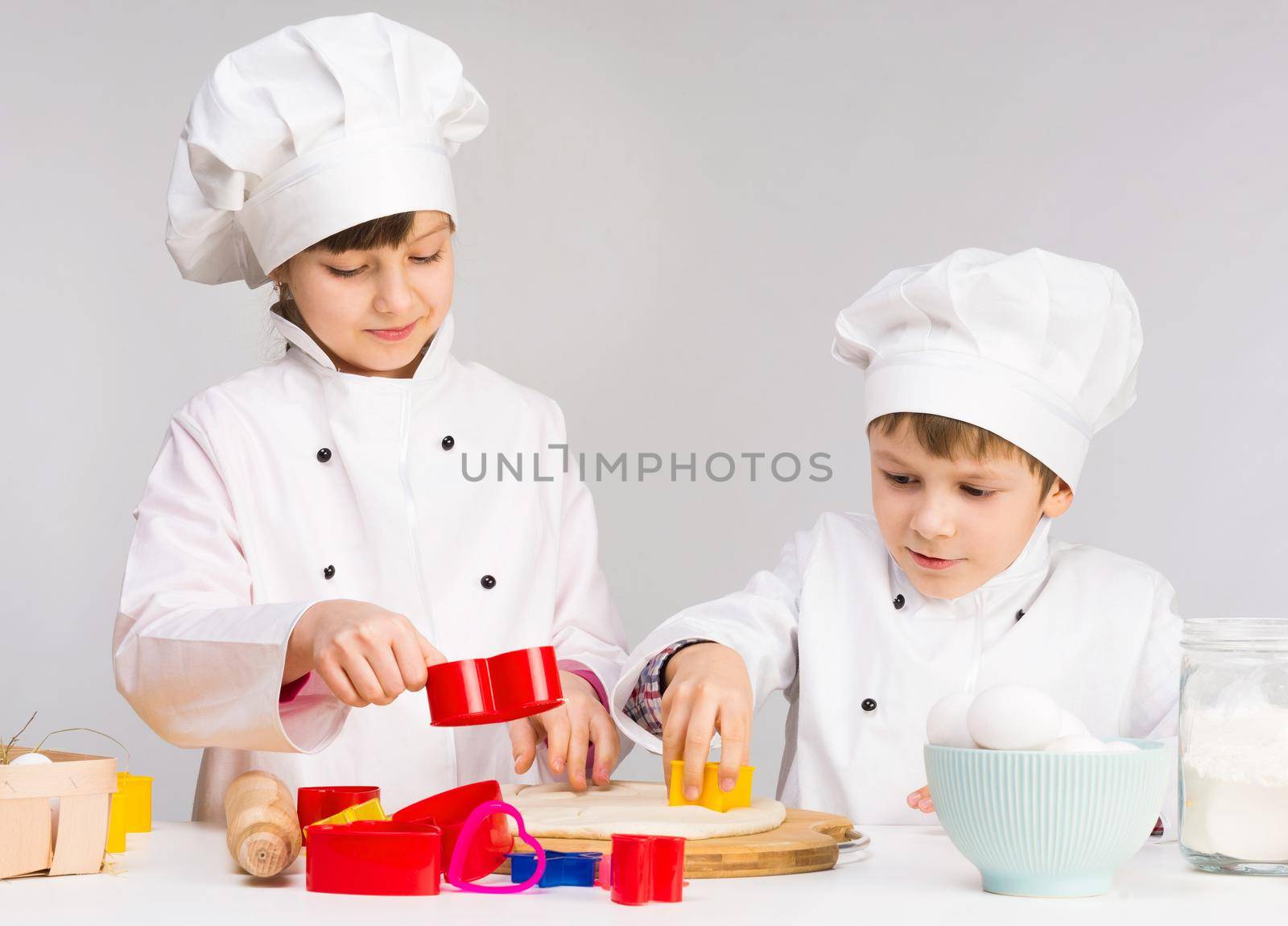 two smiling children with dough in the kitchen
