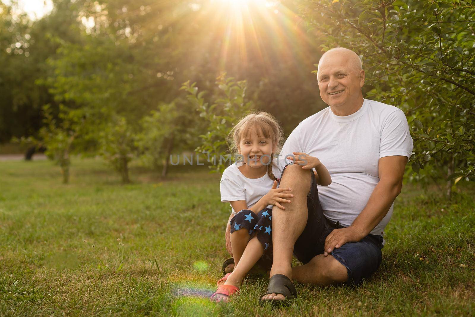 Little girl spending time with grandfather in the park.