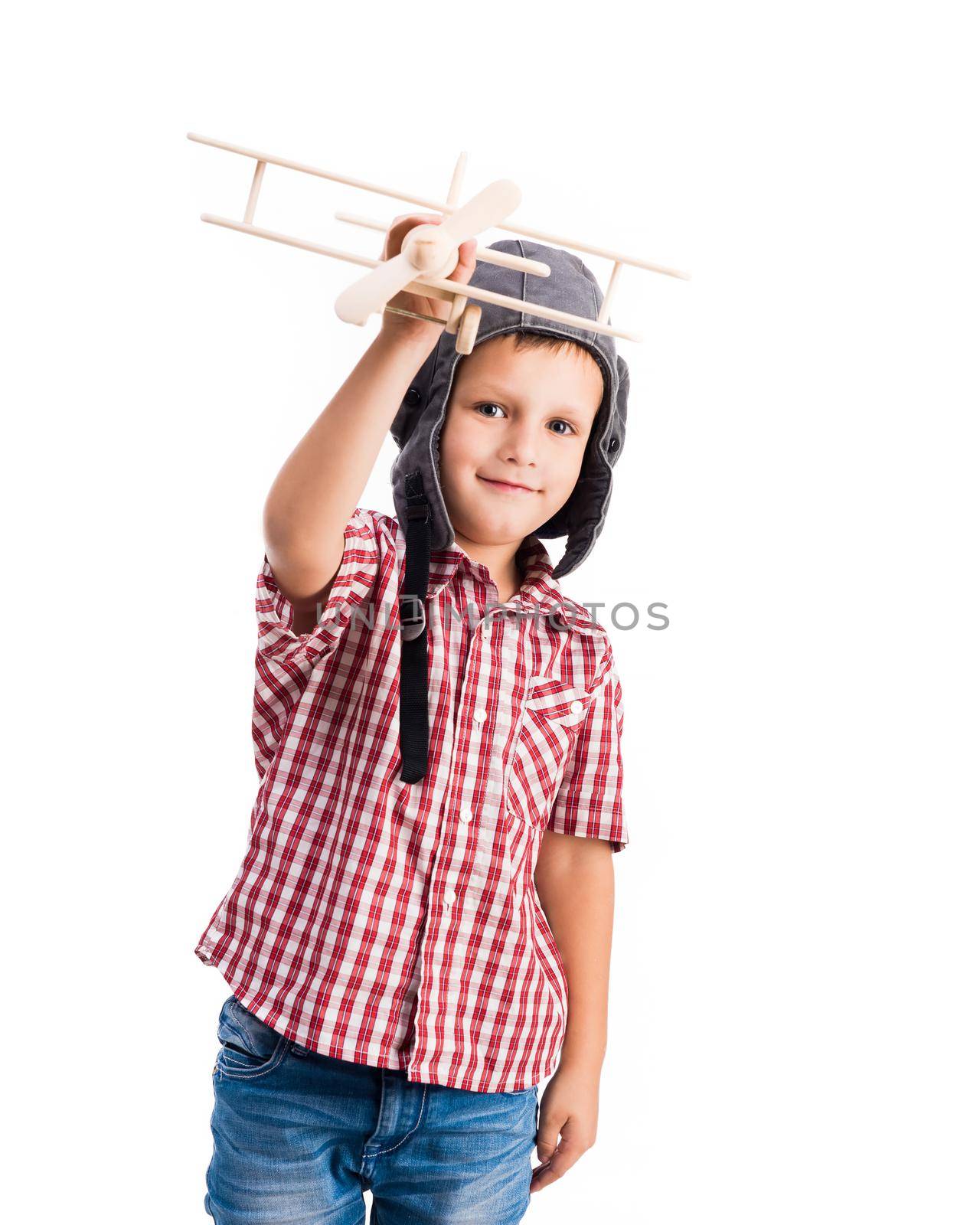 little boy holding wooden toy airplane with pilot hat isolated on white background