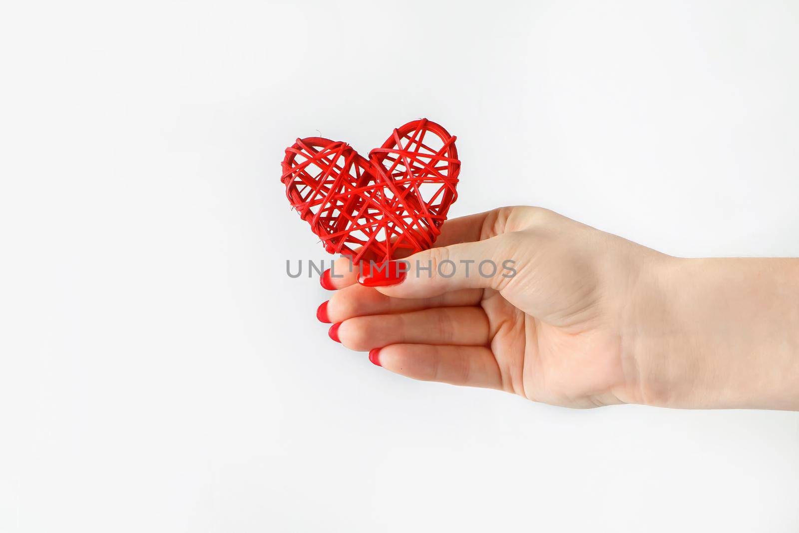 Red heart in his outstretched hand on a white background. A hand holds out a heart. Symbol of cardiology and medicine. Health concept.
