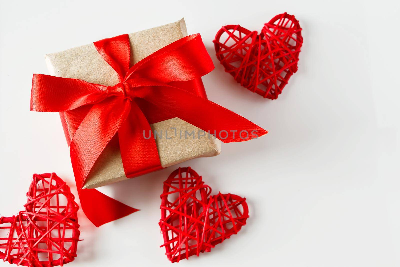 Valentine's day gift and red hearts on a white background. Valentine's day composition - gift with red ribbon and handmade hearts on a white background. Place for your text