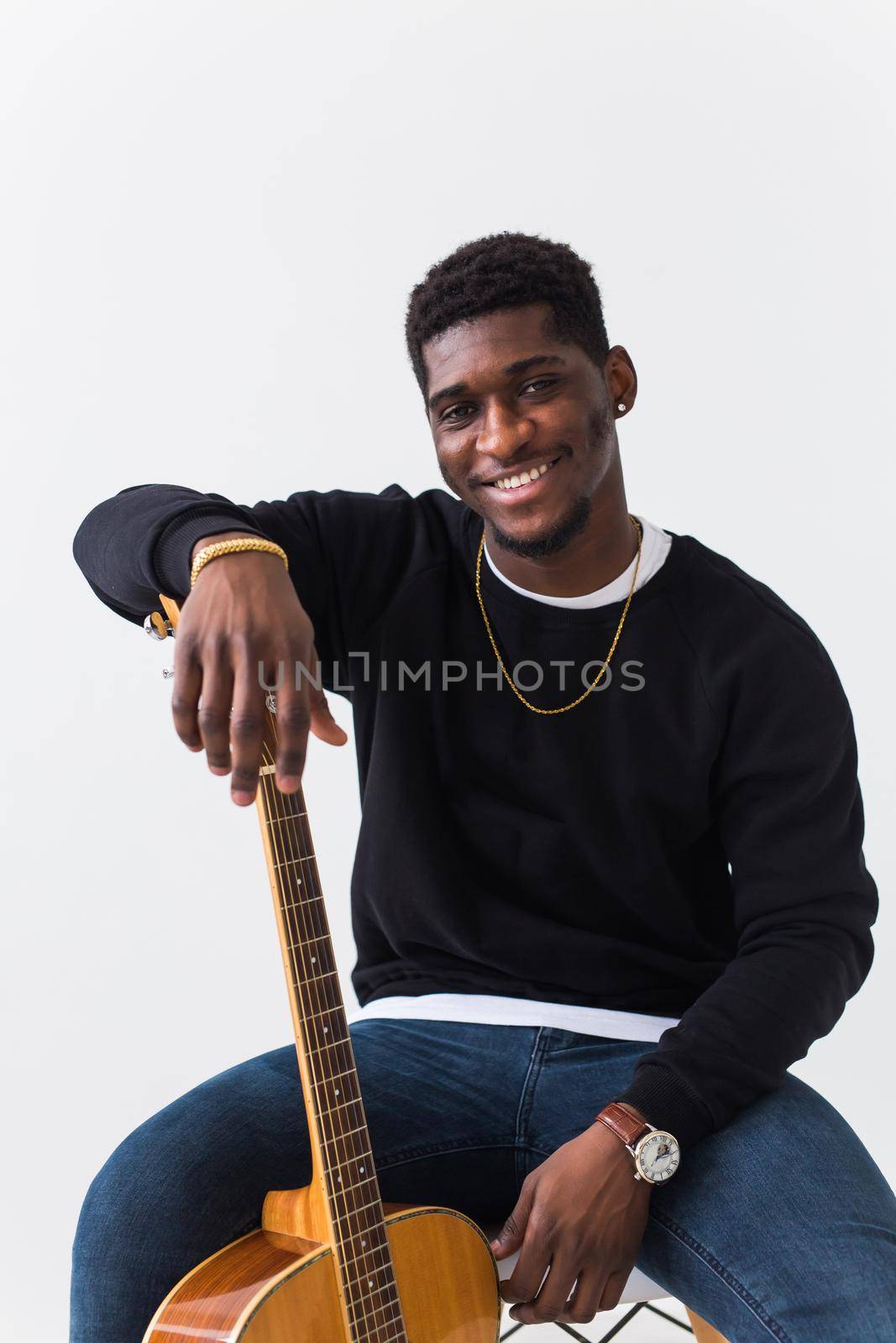Handsome African American man posing in black sweatshirt with guitar on a white background. Youth street fashion photo with afro hairstyle. by Satura86