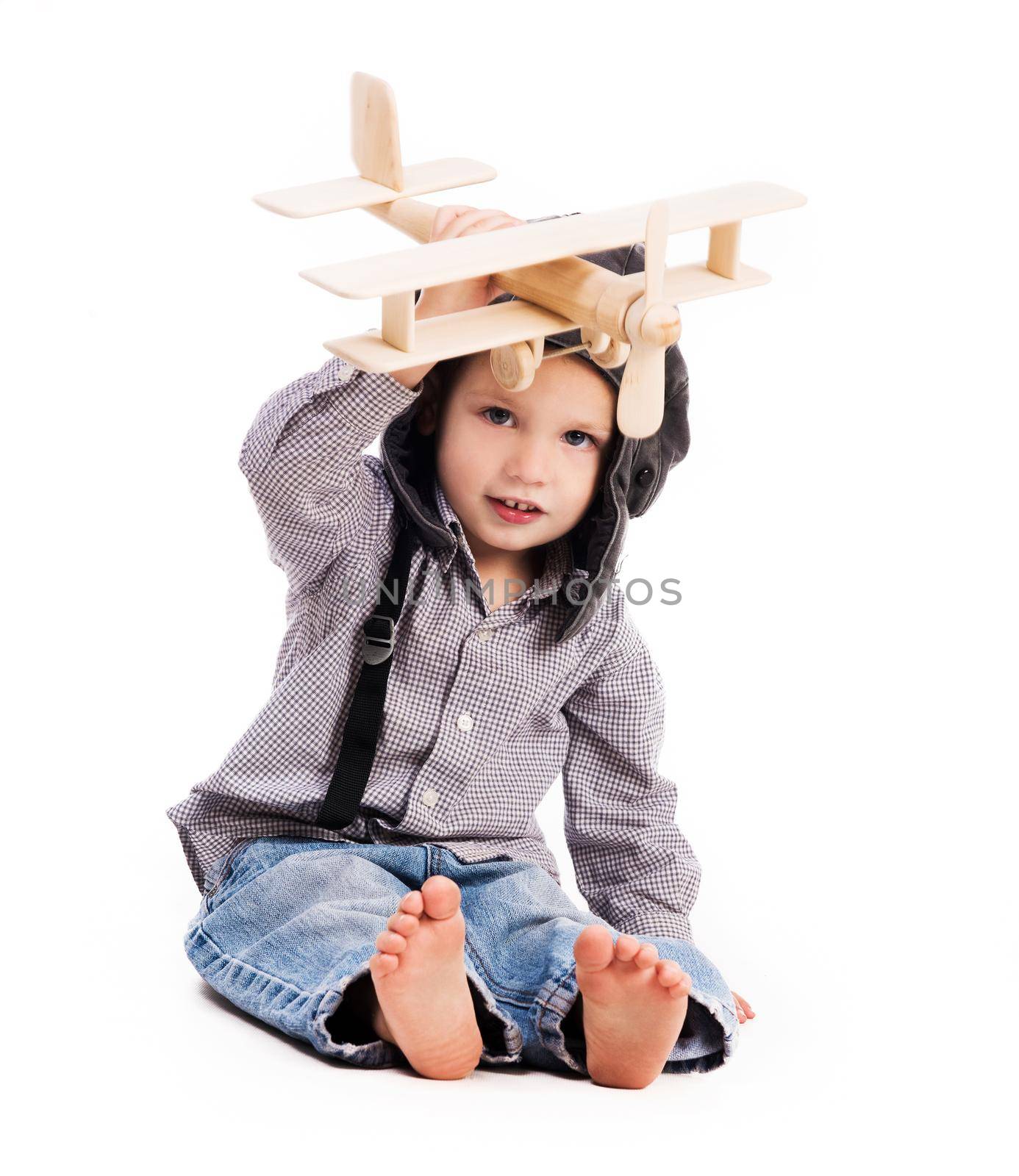 little boy with pilot hat playing toy plane isolated on white background