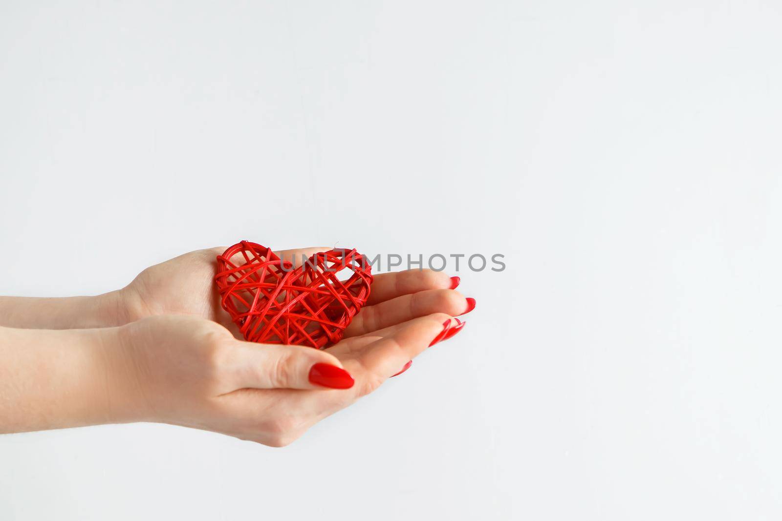 Hands holding a red heart on a white background. The concept of health and love. Hands of a young woman holding a red heart.