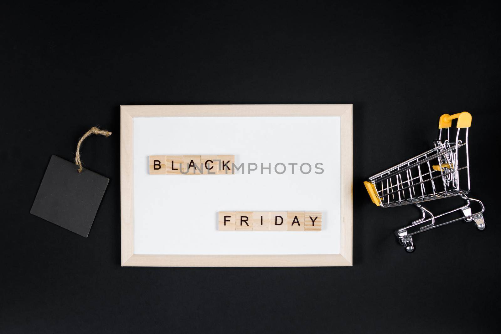 Black Friday sale. Mini shopping cart in frame on a black background. Banner for advertising.