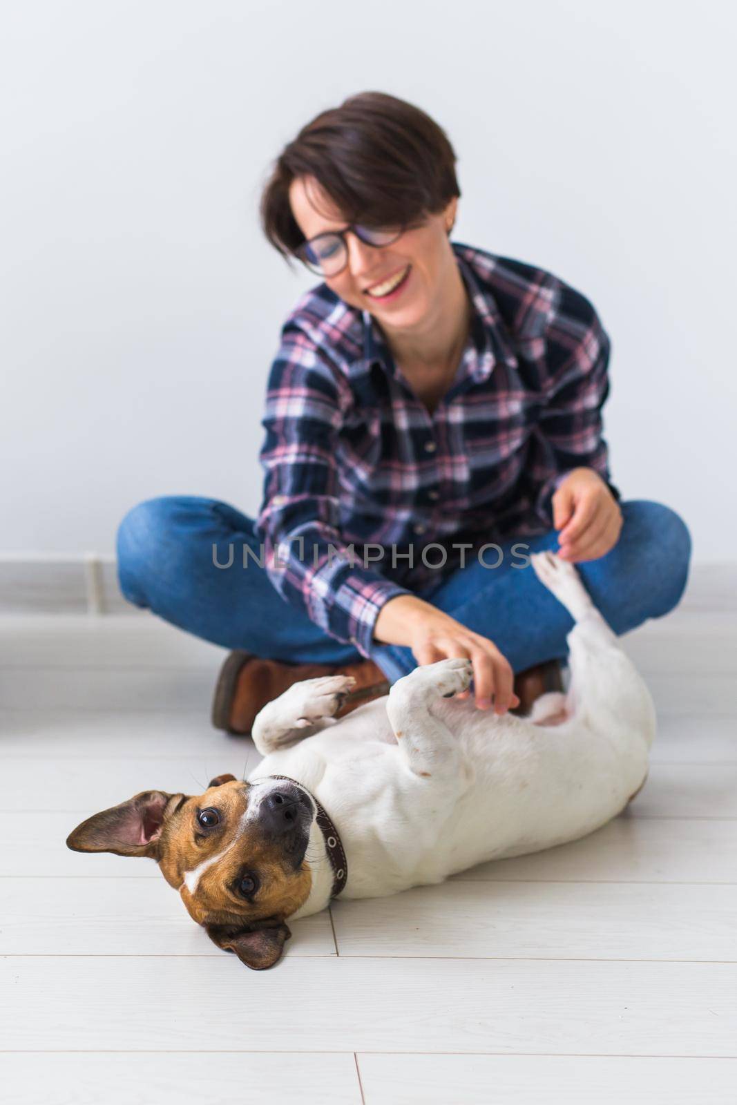 Pets owner concept - Attractive cheerful female in plaid shirt holds favourite pet. Happy woman with her jack russell terrier by Satura86
