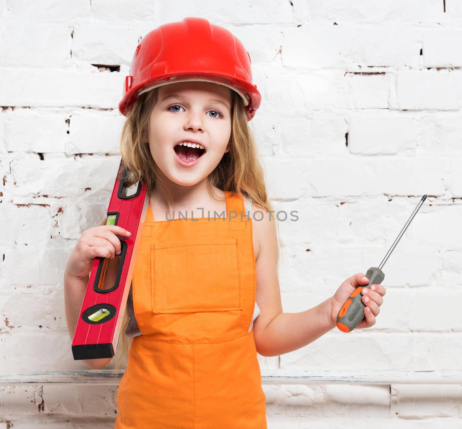 pretty girl-worker in helmet with builing level and screwdriver in hands
