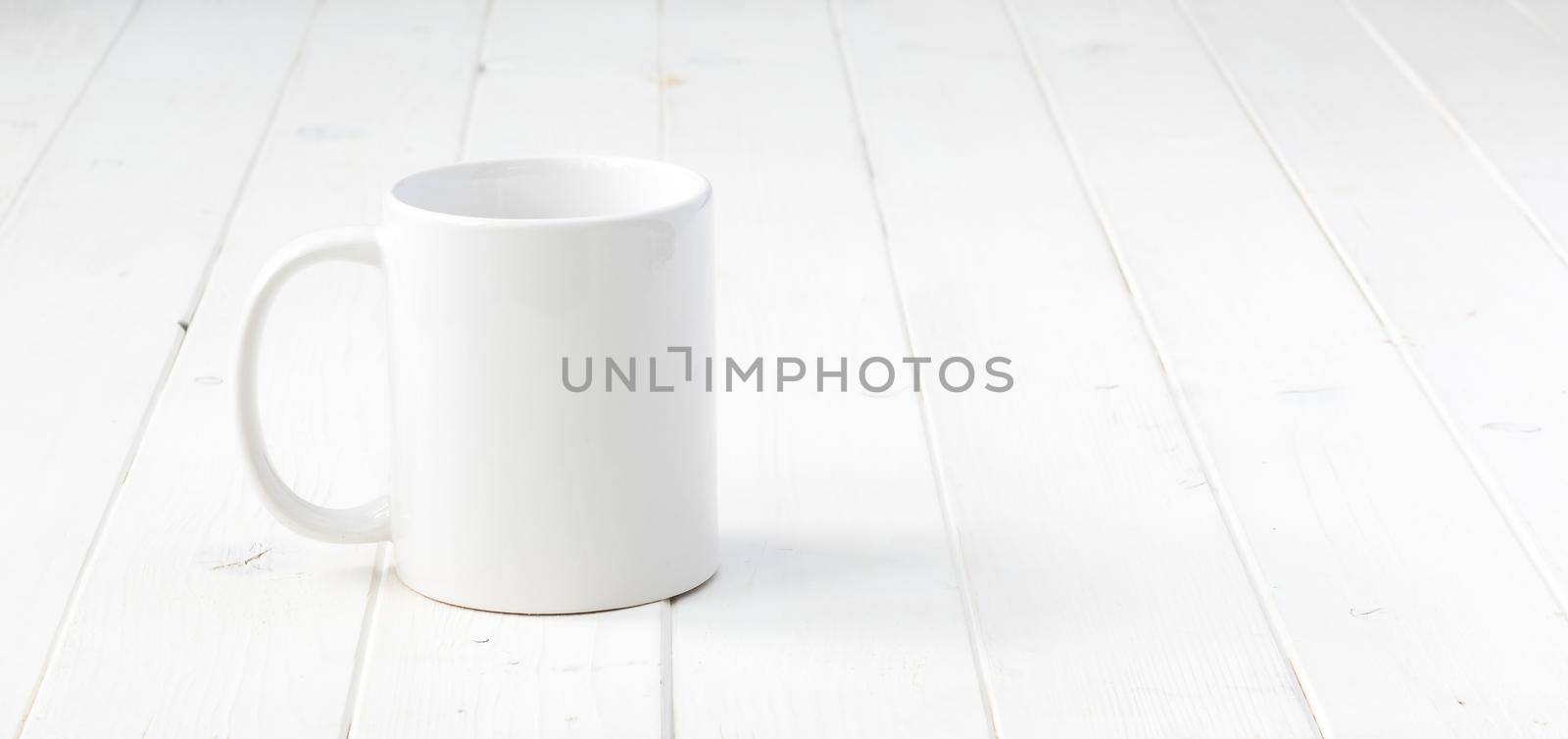 white empty cup on white planked wooden table
