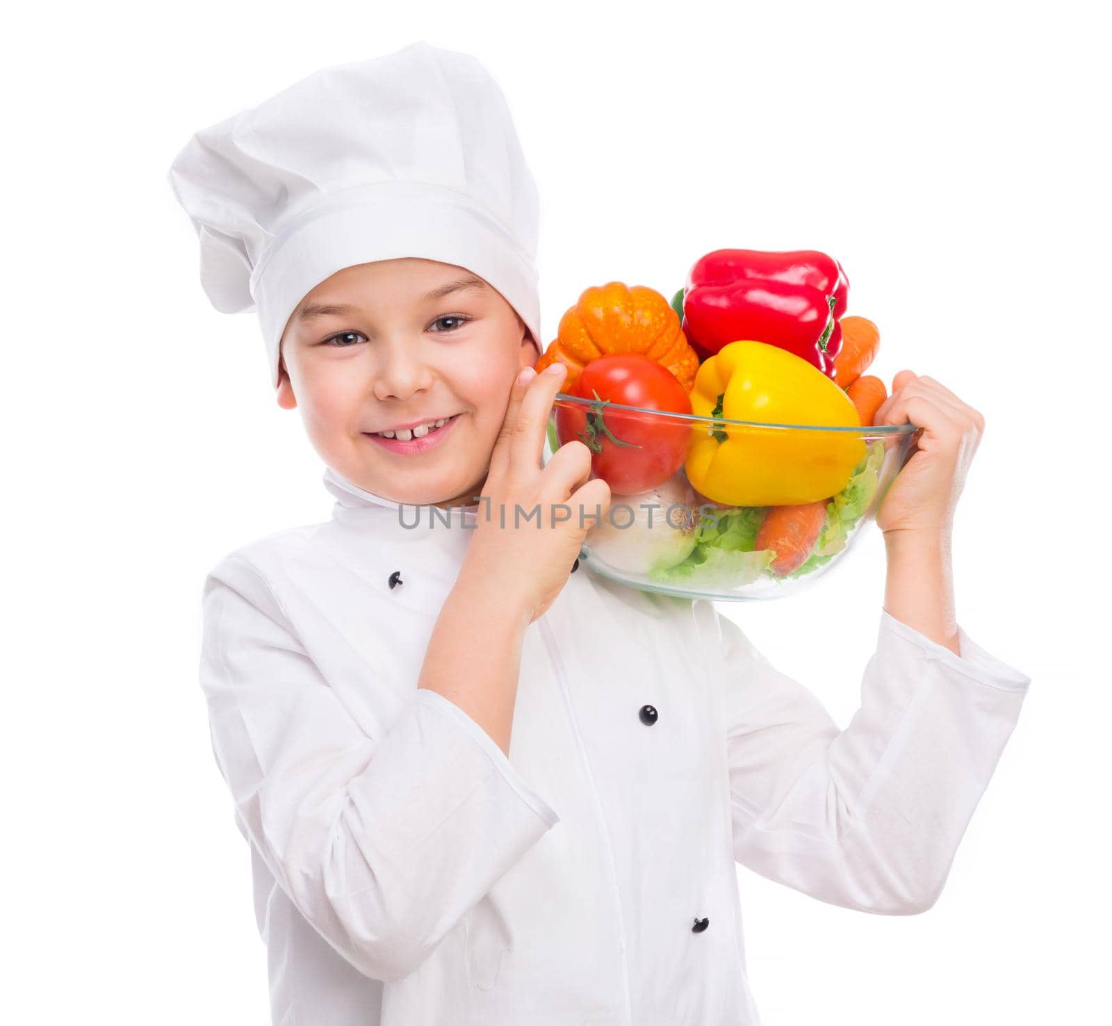 funny little boy-cook in uniform holding bowl with vegetables in hands isollated on white background