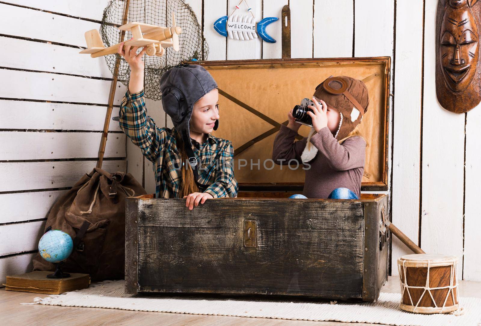 sisters playing with wooden plane in chest