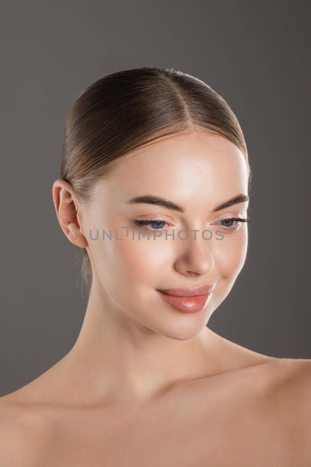 Beautiful face of young adult woman with clean fresh skin on gray backgrond