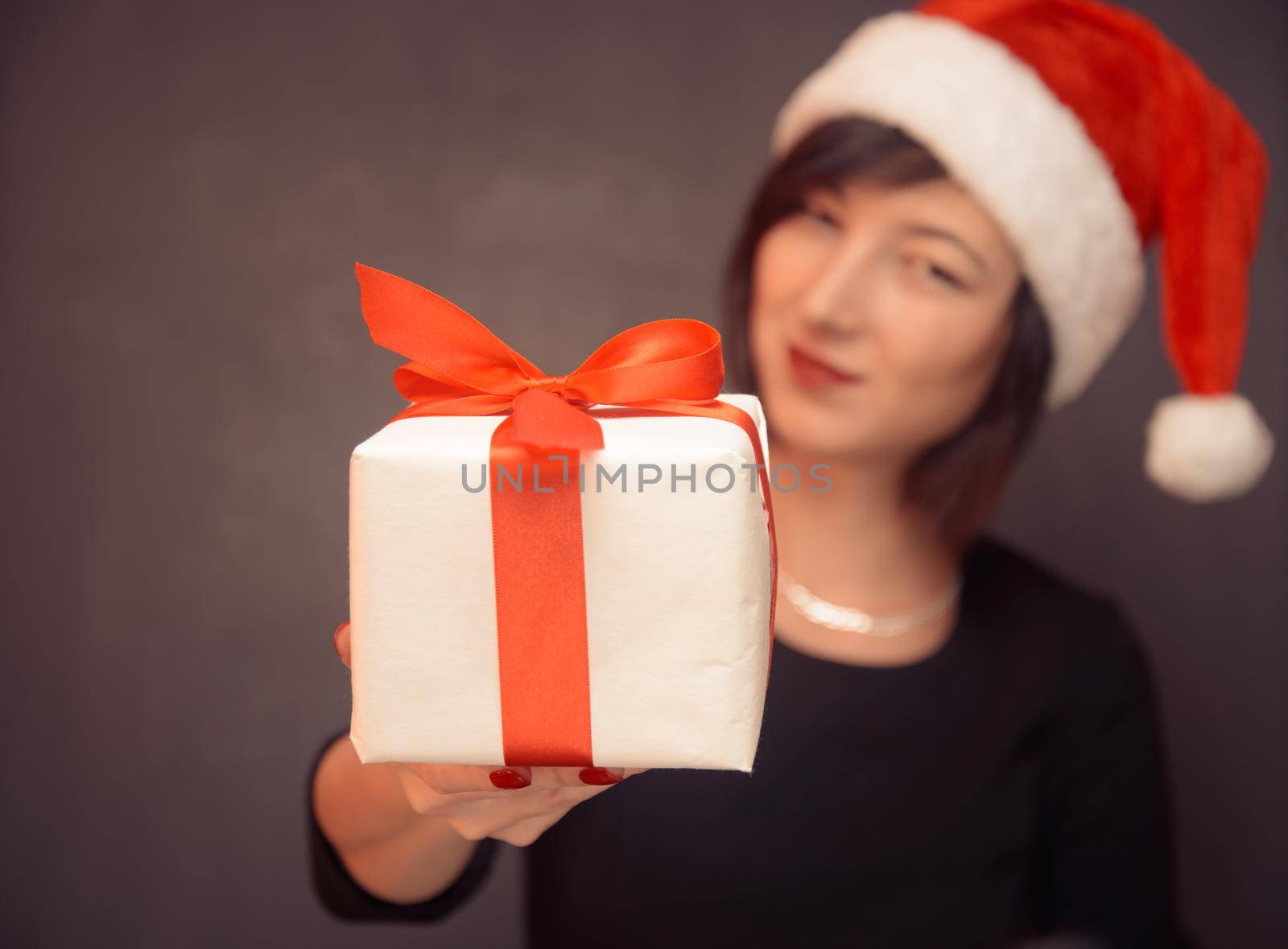 Young woman is giving a gift box with red ribbon