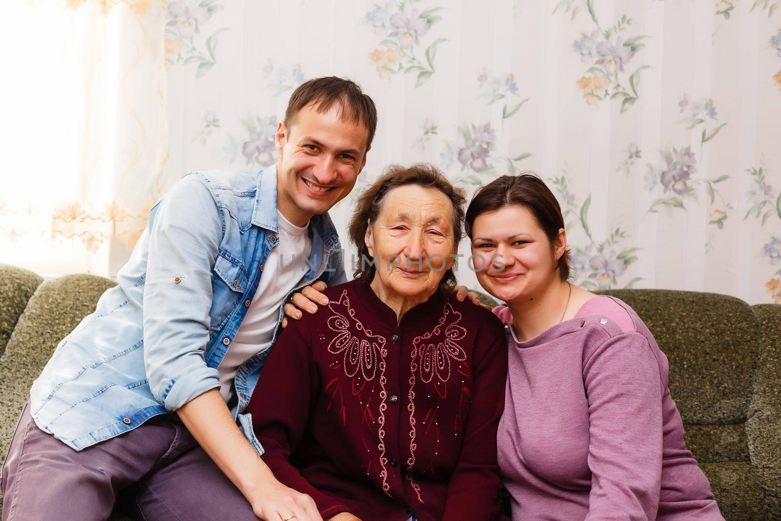 Grown up adult smiling grandchildren embraces elderly grandmother glad to see missing her, visit of loving relatives enjoy communication, cuddle as symbol of connection, love and support concept