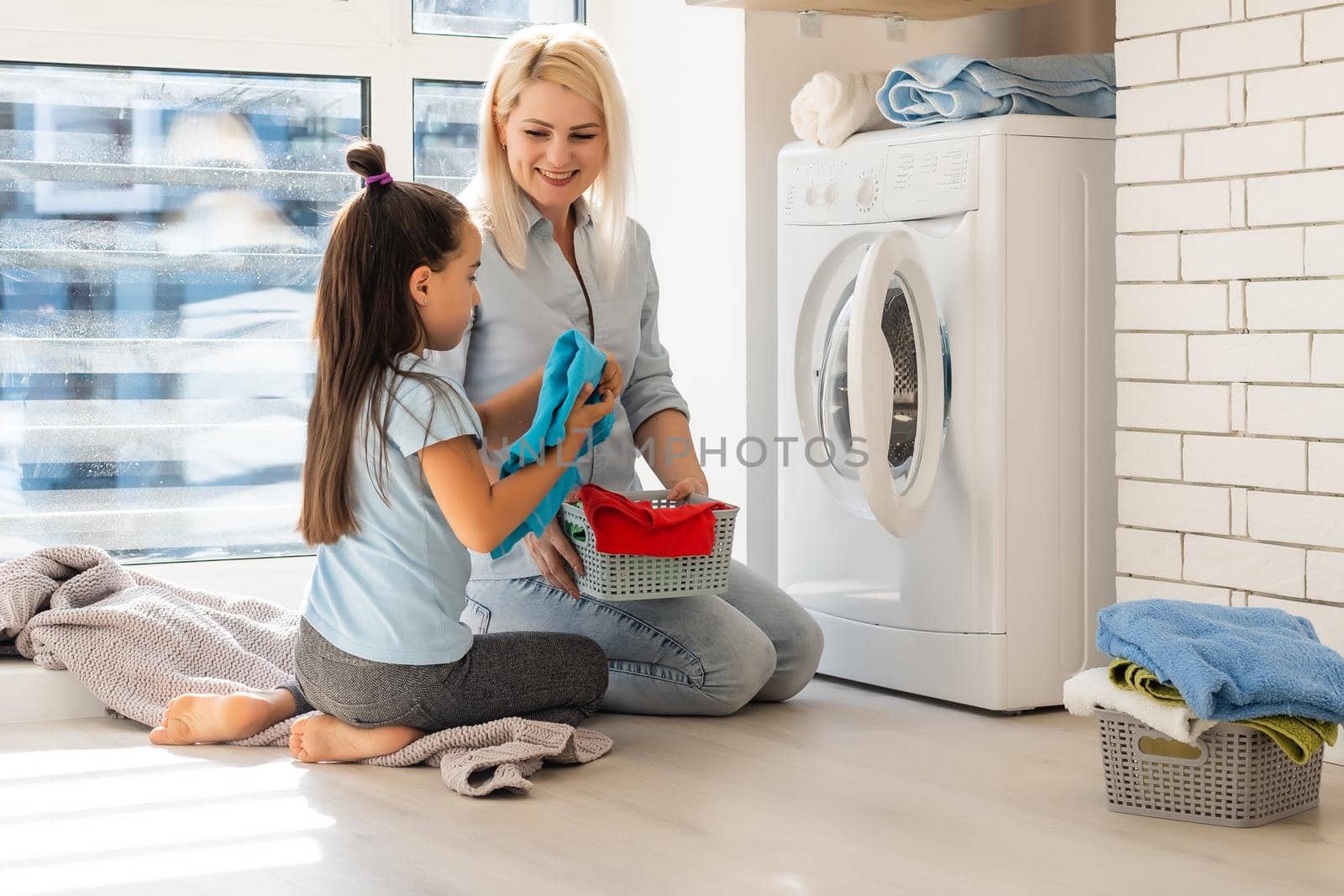 Young housewife and little girl doing laundry together