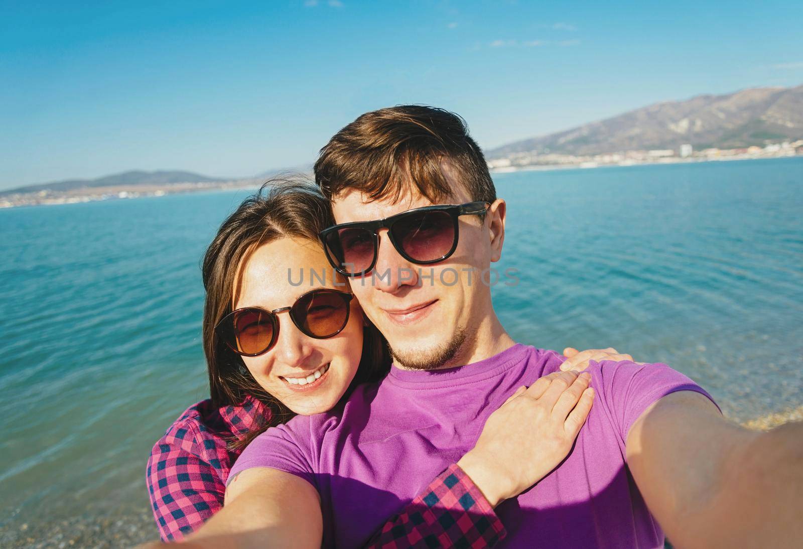 Loving couple taking photographs self-portrait on beach by alexAleksei