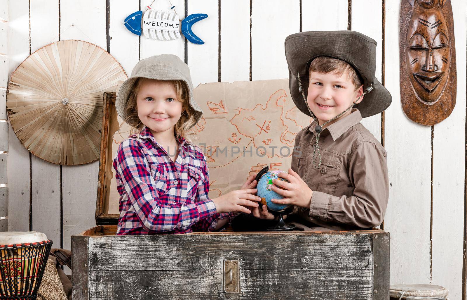 little boy and girl study globe sitting in big old chest