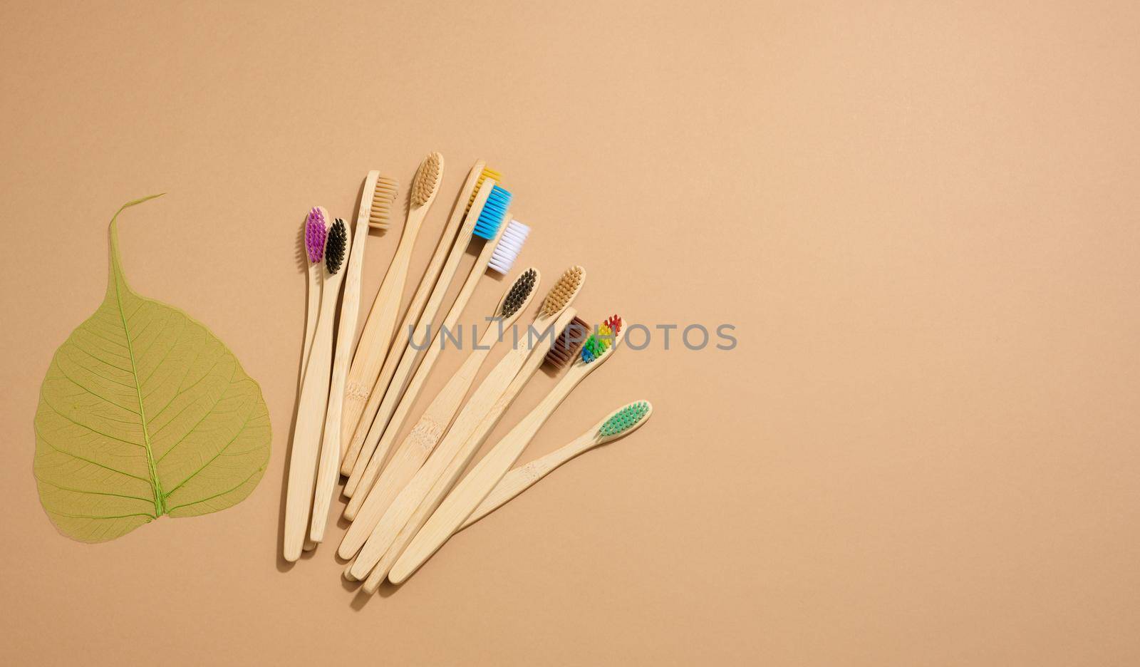 multicolored wooden toothbrushes on a brown background, plastic rejection concept, zero waste, top view by ndanko