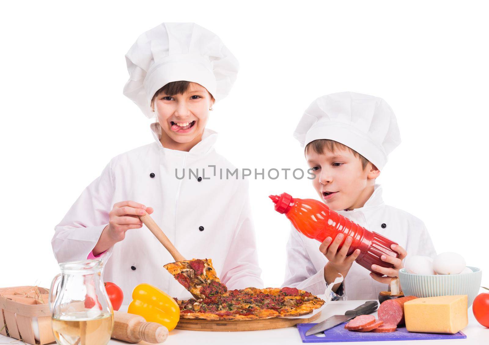 two smiling little cooks portioning fresh cooked pizza