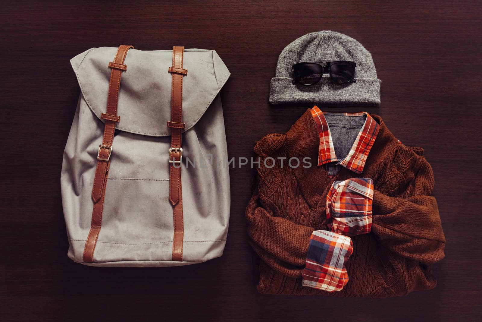 Set of male clothing and backpack in hipster style on wooden background, top view