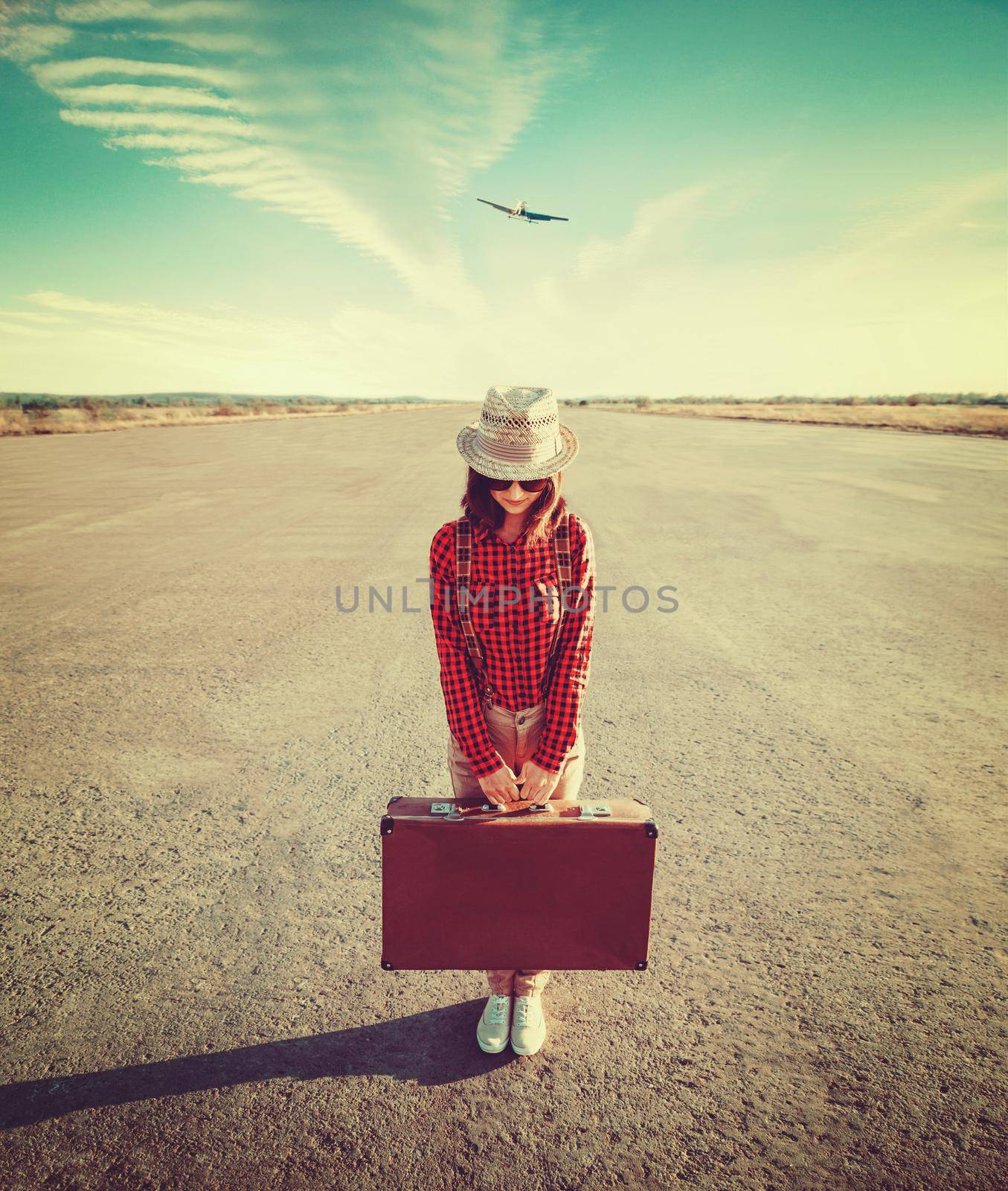 Woman traveler holds vintage suitcase on the runway. Image with instagram filter