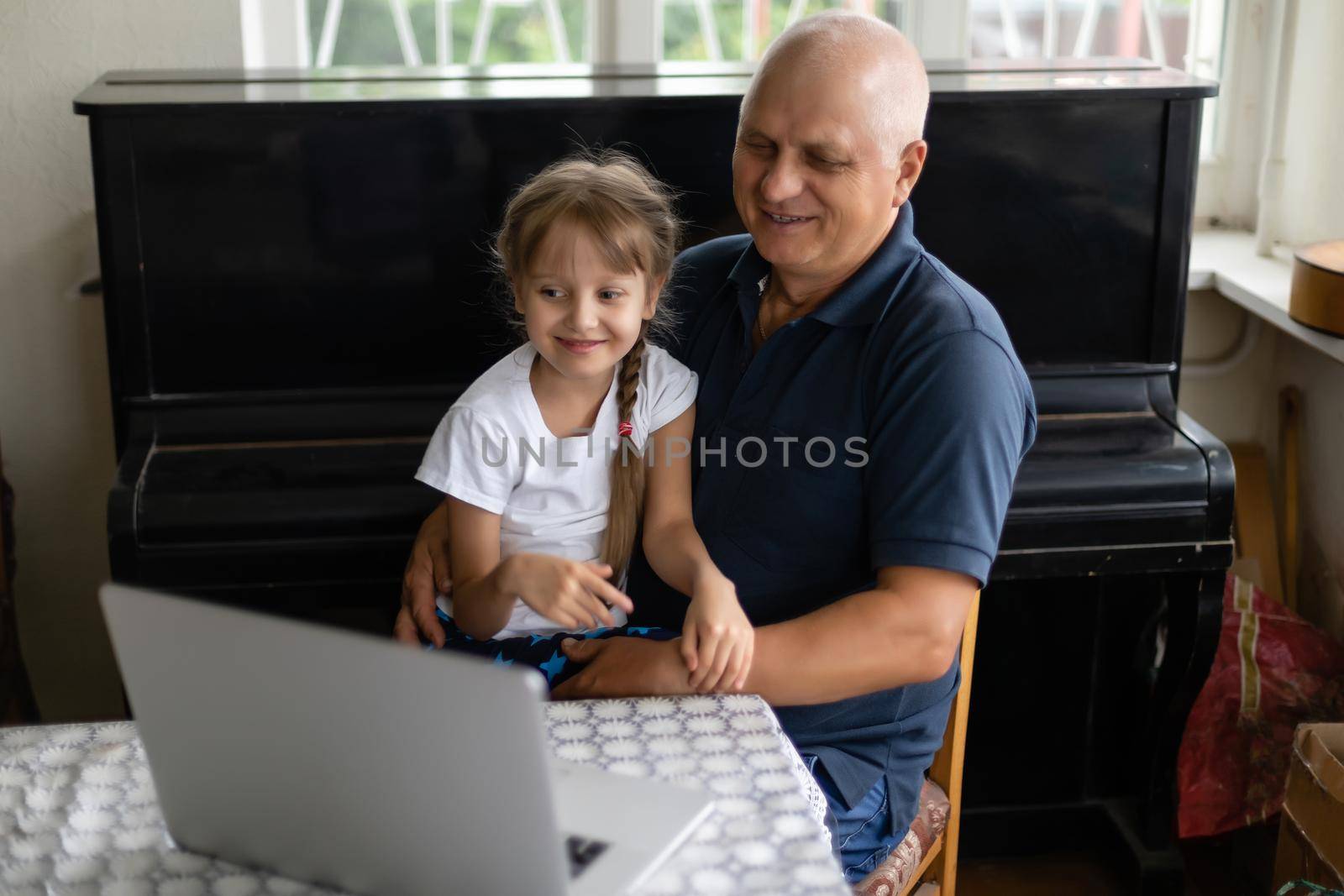Grandfather and his granddaughter using a laptop together. by Andelov13