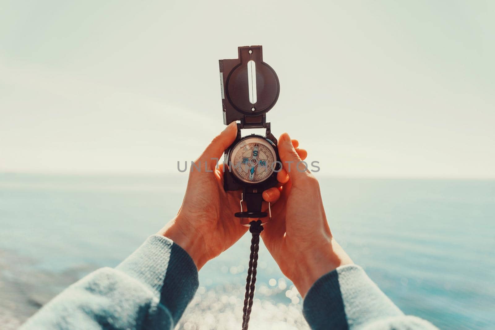 Traveler holding a compass on background of sea by alexAleksei