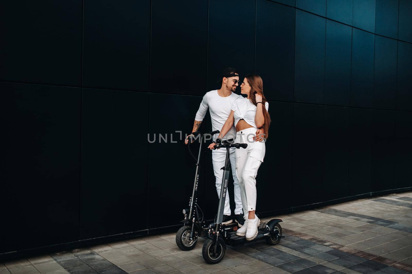 A girl and a guy are walking on electric scooters around the city, a couple in love on scooters. by Lobachad
