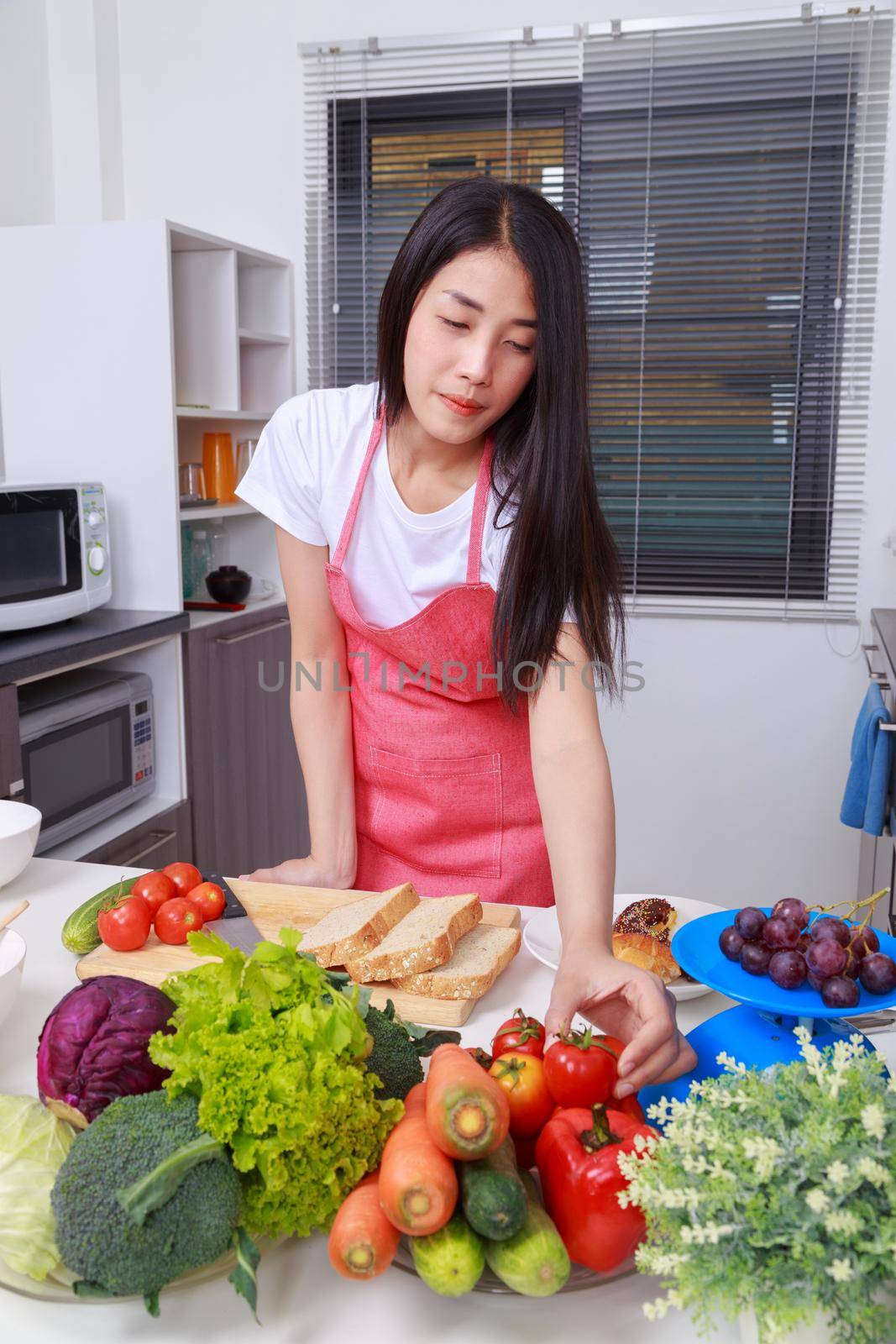 woman holding tomato in kitchen room at home