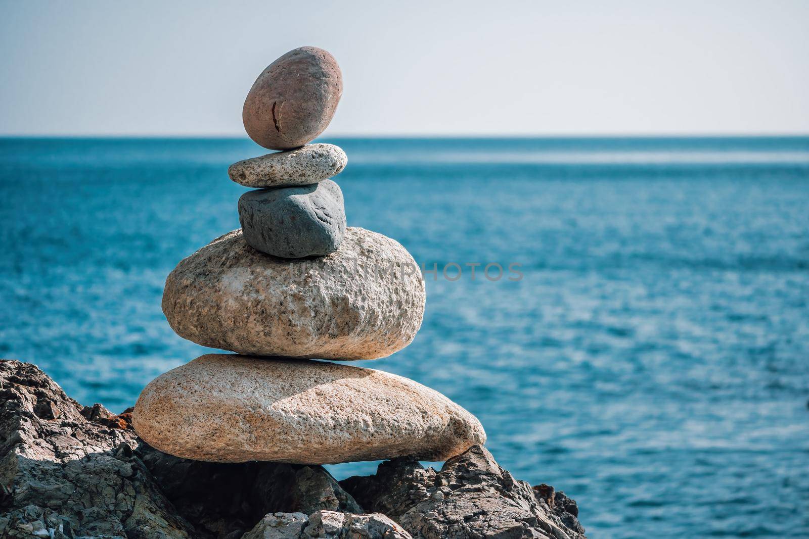 Balanced pebble pyramid silhouette on the beach on sunset. Selective focus Abstract bokeh with Sea on the background. Zen stones on the sea beach, meditation, spa, harmony, calmness, balance concept