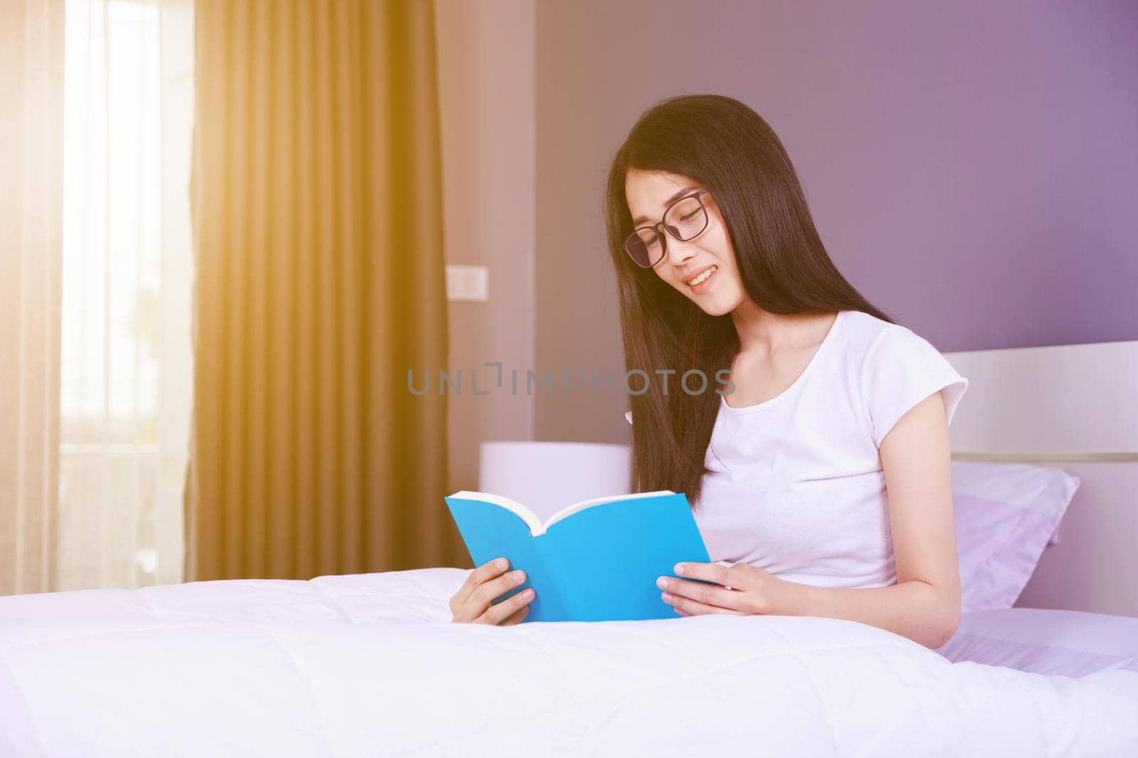 woman reading a book on bed in the bedroom at home