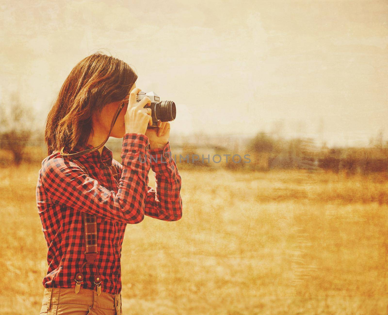 Young woman takes photographs with vintage photo camera in autumn outdoor. Vintage image