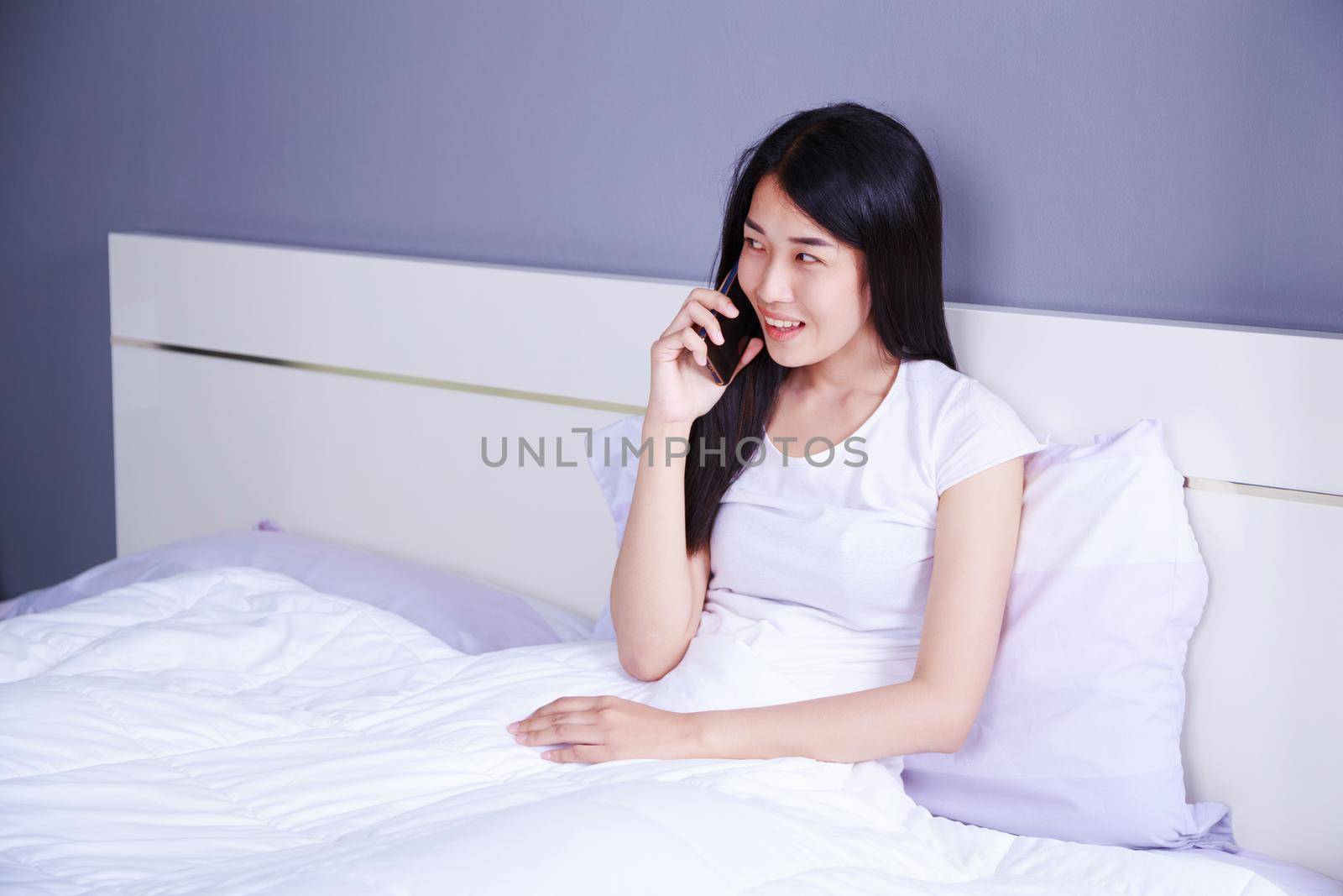 woman talking on cellphone on bed in the bedroom