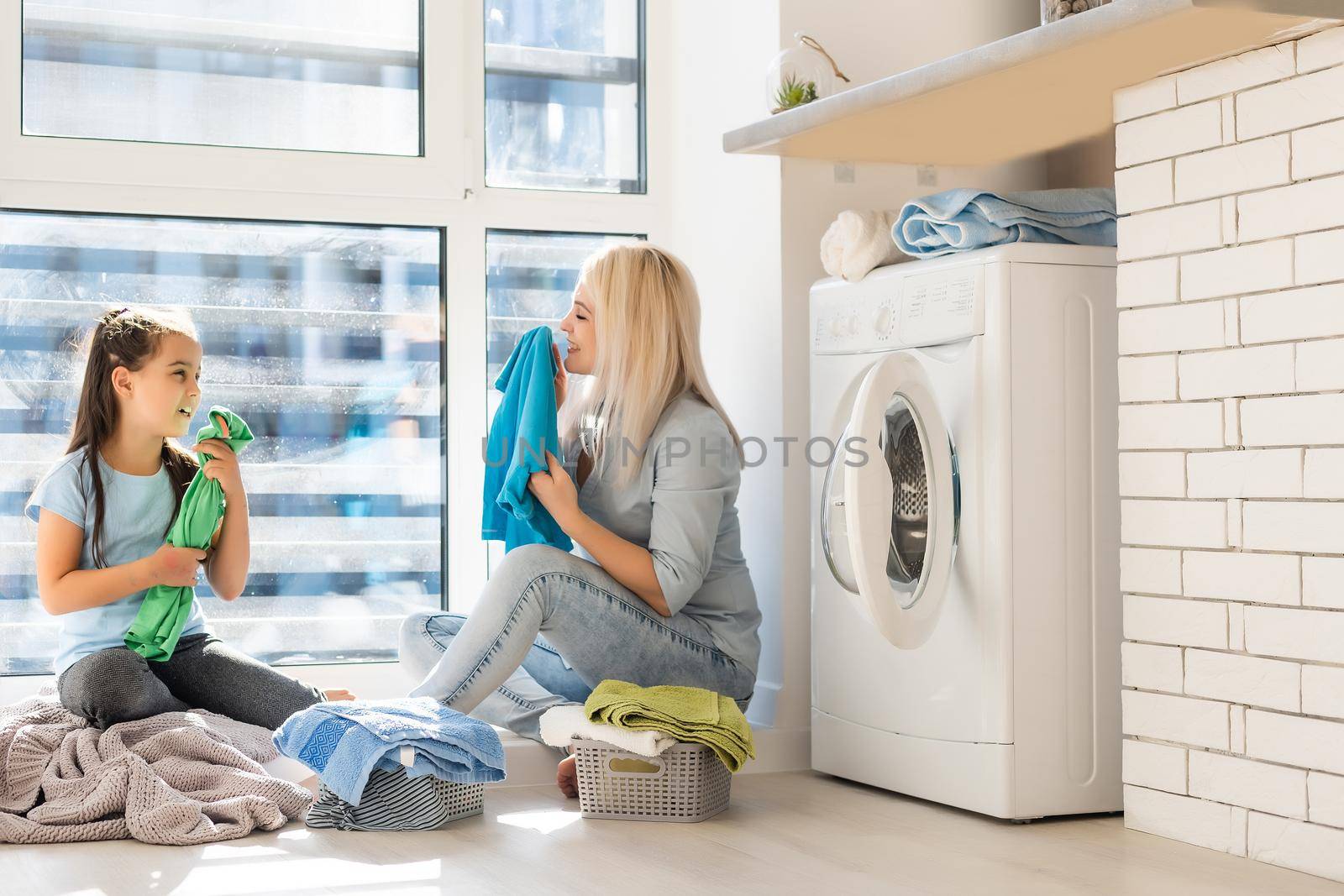 family mother and child girl little helper in laundry room near washing machine and dirty clothes