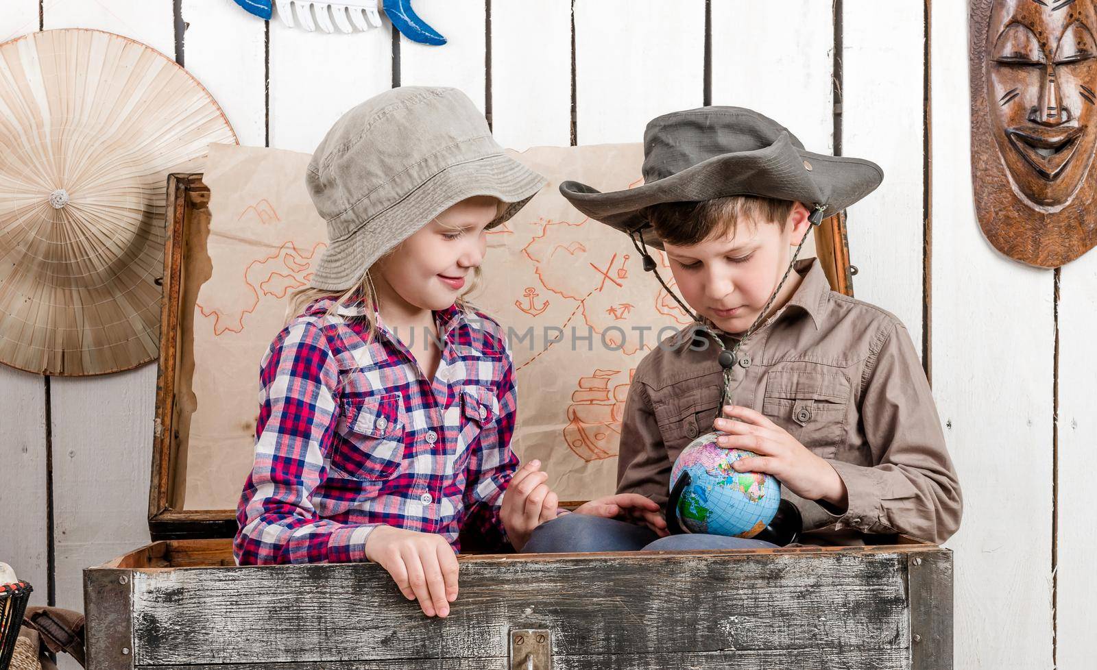little boy and girl study globe in big chest by GekaSkr