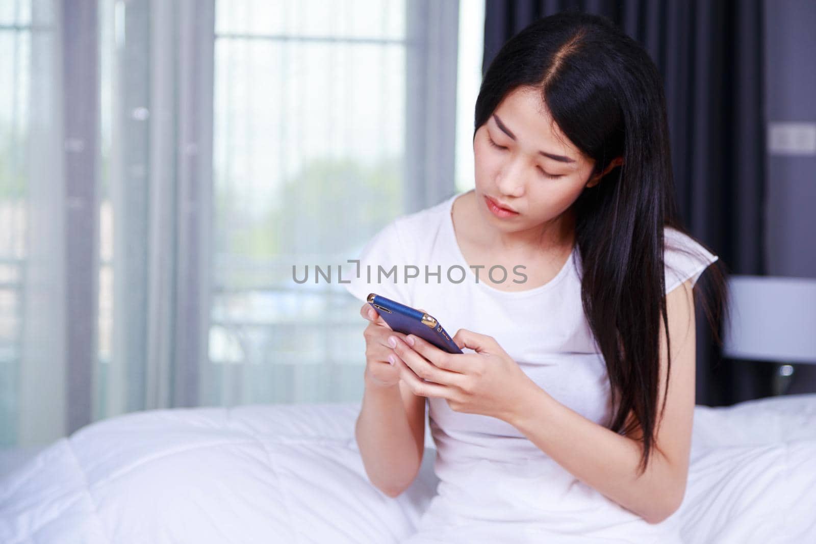 woman using a phone in her hand on bed in the bedroom