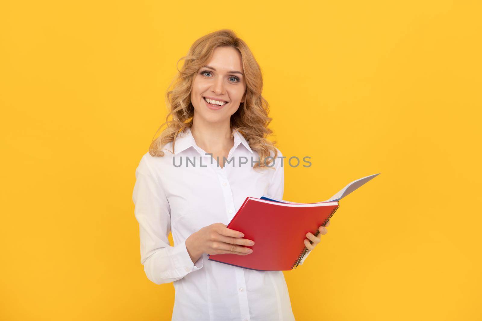 happy blonde businesswoman woman in white shirt making notes in notepad or notebook, student by RedFoxStudio