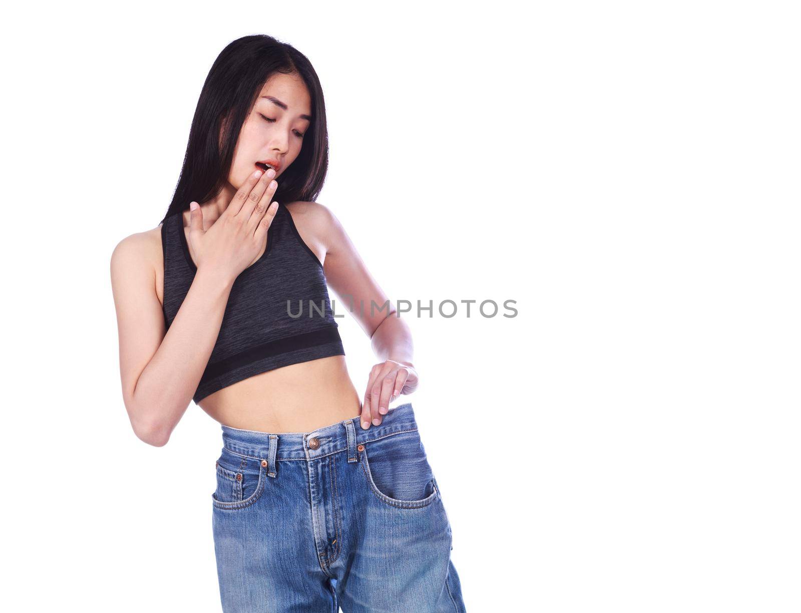 Shocked slim fitness woman in old jeans after losing weight isolated on a white background