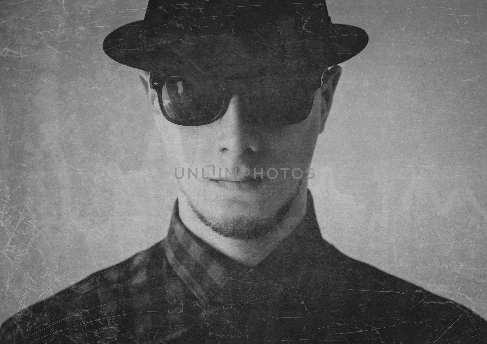 Portrait of serious man in sunglasses and hat. Image with old effect, textured image. Black and white image