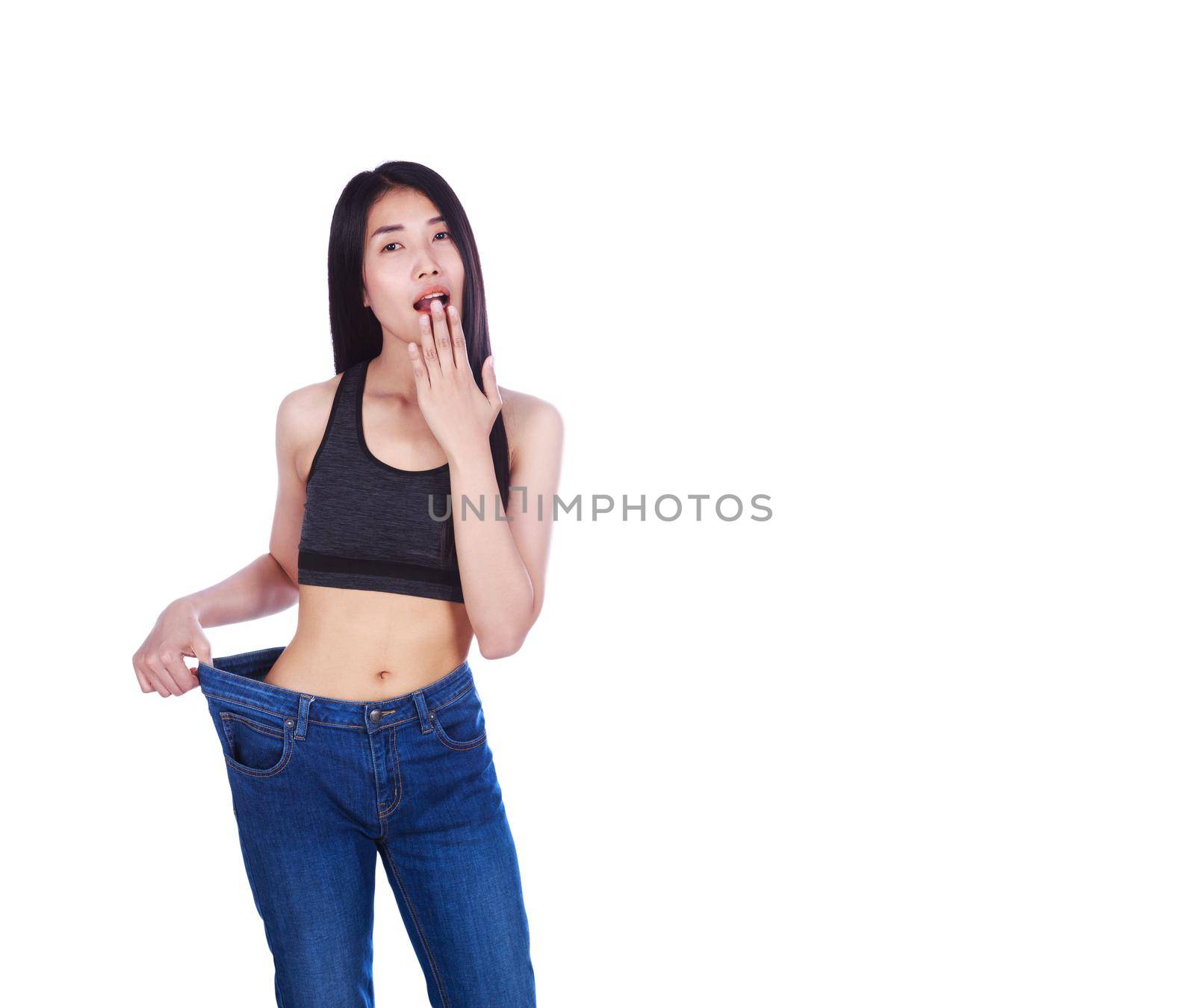 Shocked slim fitness woman in old jeans after losing weight isolated on a white background