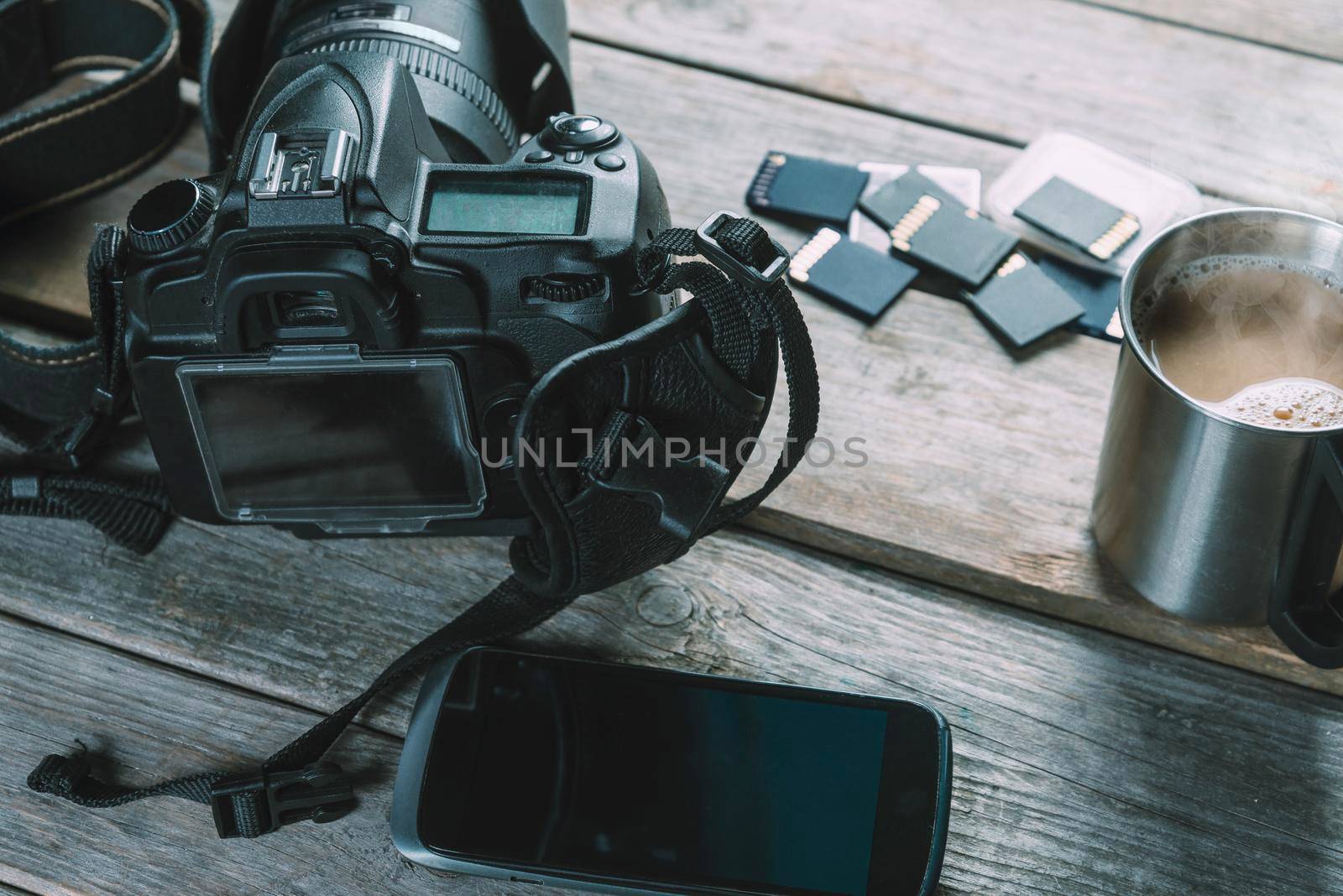 Digital photo camera, memory cards and mobile phone on wooden table