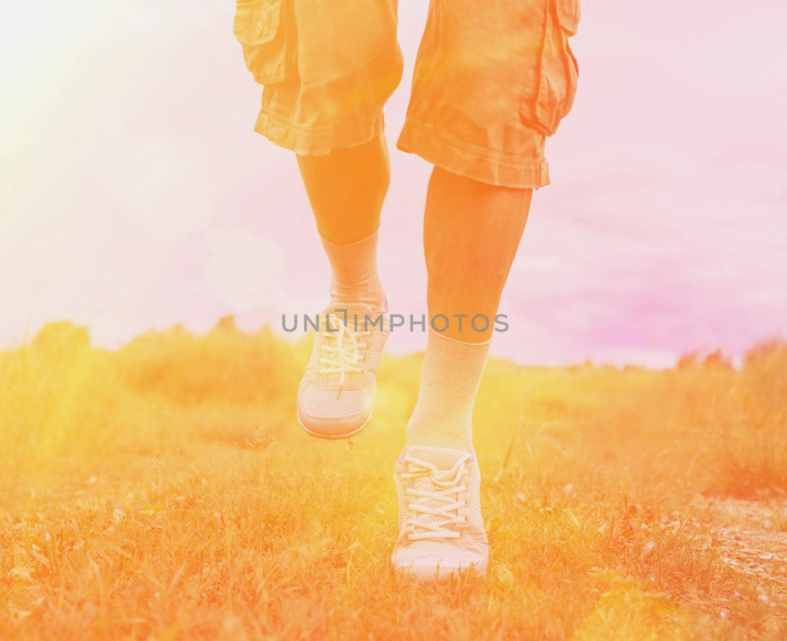 Man running on footpath in summer, view of legs. Image with sunlight effect