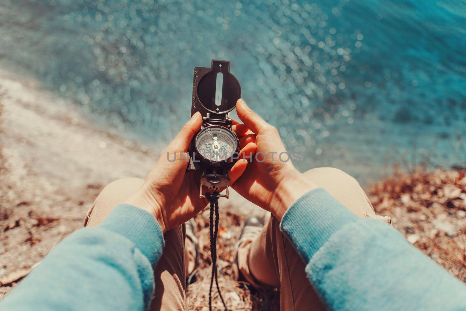 Traveler holding a compass on coastline by alexAleksei