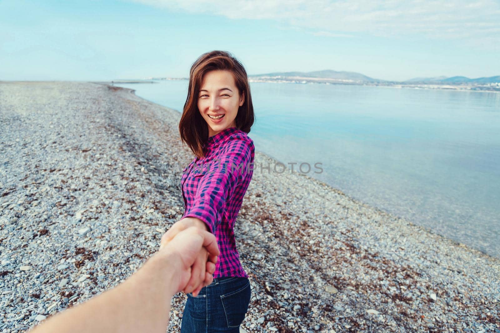 Smiling woman leading man on beach near the sea by alexAleksei