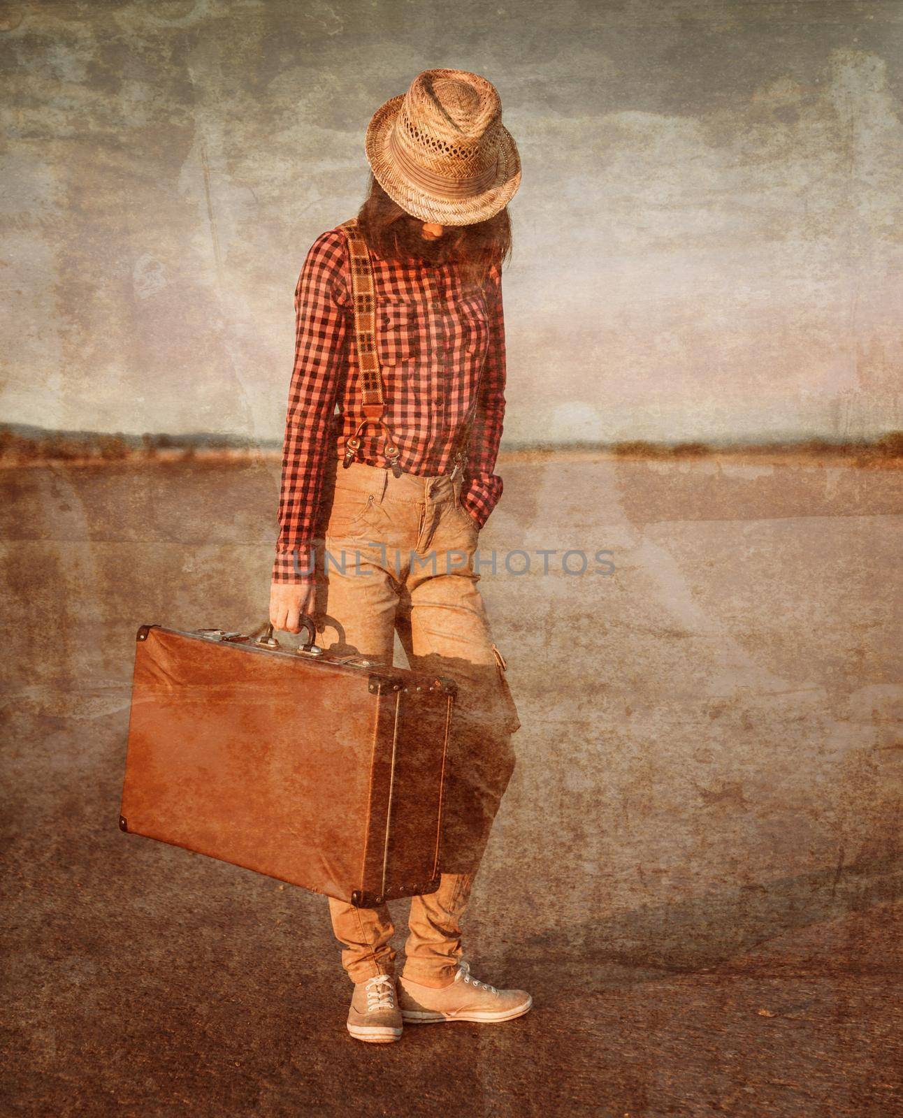 Hipster woman in hat stands with retro suitcase on road. Vintage image